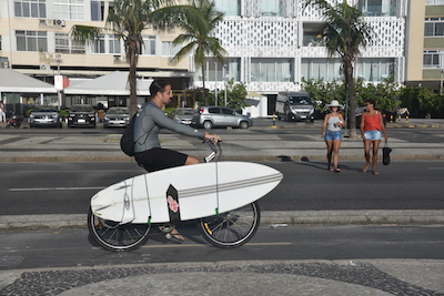 photo de surfeur transportant sa planche sur son vélo