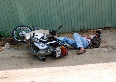 Photo d'un ivrogne dormant à côté de sa moto tombée à terre