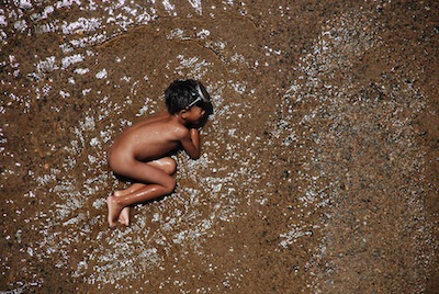 photo en contre plongée d'un enfant se baignant dans une rivière